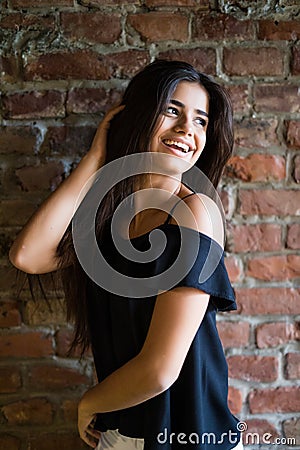 Young beautiful happy woman in casual clothes against brick wall Stock Photo