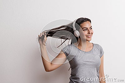 Young beautiful happy woman with headphones in studio. Copy space. Stock Photo