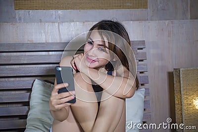 Young beautiful and happy girl sitting on bed smiling and flirti Stock Photo