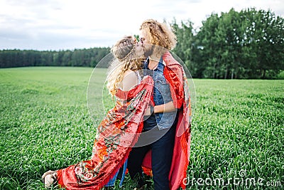 Young beautiful hippie couple walking in green summer field Stock Photo