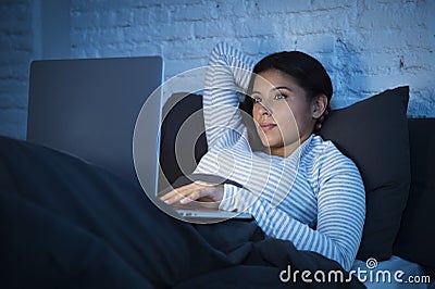 Young beautiful hispanic woman on bed at home working relaxed on laptop computer at night Stock Photo