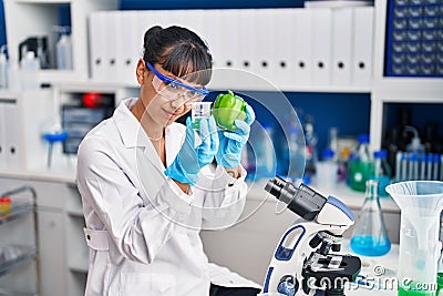 Young beautiful hispanic woman scientist holding pepper measuring liquid at laboratory Stock Photo