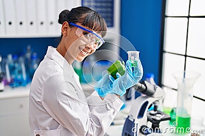 Young beautiful hispanic woman scientist holding pepper measuring liquid at laboratory Stock Photo