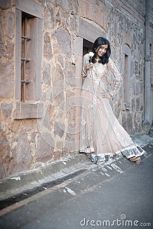 Young beautiful Indian Woman standing against stone wall outdoors Stock Photo