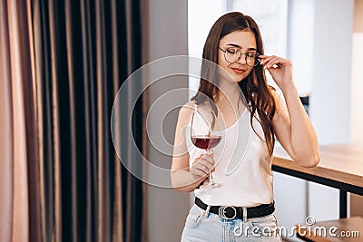 Young and beautiful lady in glasses is drinking red wine at home. Freestyle woman. Freelancer female relax Stock Photo