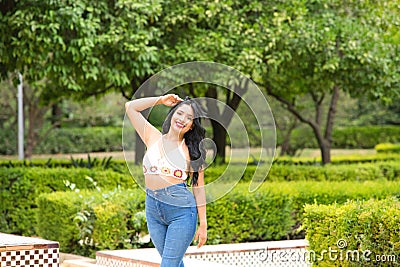 Young and beautiful Latin woman from South America walks among the trees and vegetation of the park. The woman is smiling and Stock Photo