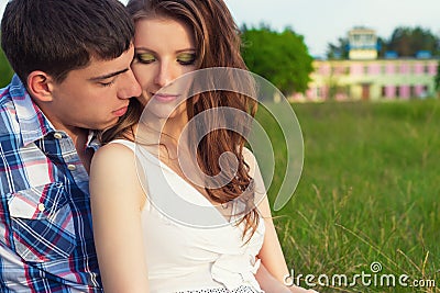 Young beautiful loving happy couple sitting in the box on the grass in the warm evening summer day Stock Photo