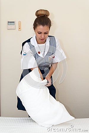 Young and beautiful maid girl putting pillowcase on pillow Editorial Stock Photo