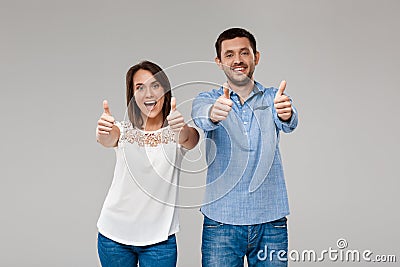 Young beautiful married couple posing, showing okay over grey background. Stock Photo