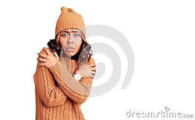Young beautiful mixed race woman wearing wool sweater and winter hat shaking and freezing for winter cold with sad and shock Stock Photo