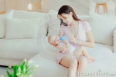 Young beautiful mother bottle feeding her little son at home Stock Photo