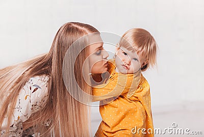 Young beautiful mother wants to kiss her little daughter. Mom and Her Child Having Fun together Stock Photo
