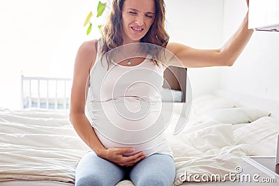 Young beautiful pregnant woman, in pain with labor contraction Stock Photo