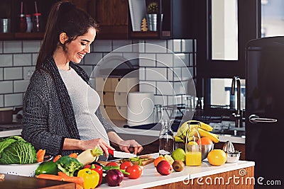 Young beautiful pregnant woman preparing healthy meal with fruites and vegetables Stock Photo