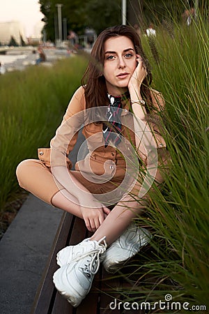 Young beautiful red haired gen z girl wearing slim fitted women beige khaki coverall overall denim jumpsuit or flight Stock Photo