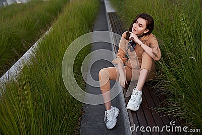 Young beautiful red haired gen z girl wearing slim fitted women beige khaki coverall overall denim jumpsuit or flight Stock Photo