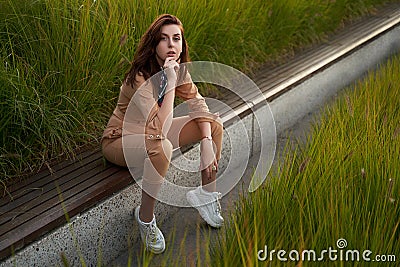 Young beautiful red haired gen z girl wearing slim fitted women beige khaki coverall overall denim jumpsuit or flight Stock Photo