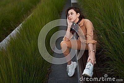 Young beautiful red haired gen z girl wearing slim fitted women beige khaki coverall overall denim jumpsuit or flight Stock Photo