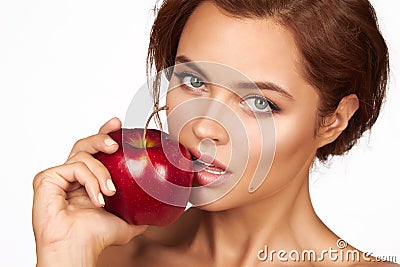 Young beautiful girl with dark curly hair, bare shoulders and neck, holding big red apple to enjoy the taste and are dieting, Stock Photo