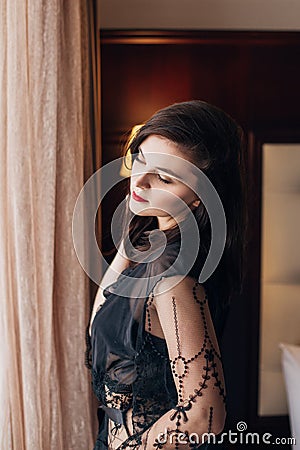 Young beautiful woman in a black lace dressing gown posing in a room Stock Photo