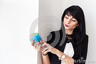 Young Beautiful smiling brunette woman dressed in black business suit holding a globe of the planet Earth Stock Photo