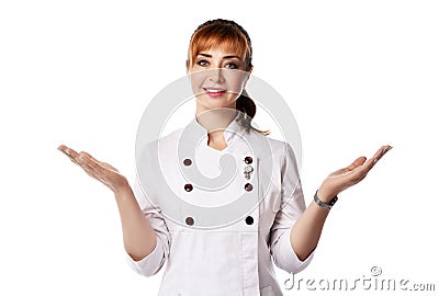 Young beautiful smiling red-haired woman doctor or nurse in white special uniform standing and shrugging with hands Stock Photo
