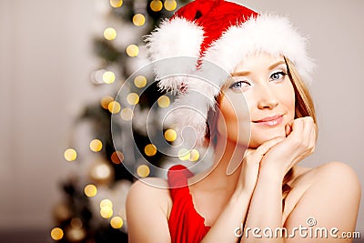 Young beautiful smiling santa woman near the Christmas tree. Fashionable luxury girl celebrating New Year. Beauty luxury trendy b Stock Photo
