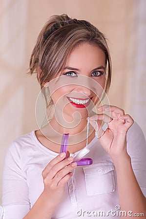 Young beautiful smiling woman holding a menstruation cotton tampon in one hand and with her other hand a plastic purple Stock Photo