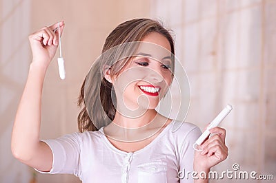 Young beautiful smiling woman holding two menstruation cotton tampons in a blurred background Stock Photo