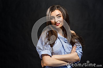 Young beautiful smiling woman striped blue and white dress shirt posing over black background Stock Photo