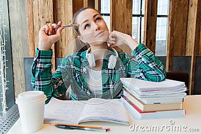 Young beautiful student girl is doing her homework or preparing to the exams siting with books copybooks Stock Photo