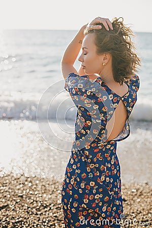 Woman in blue dress posing at beach on sunset. Stock Photo