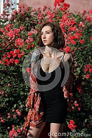 Young beautiful tattooed woman with closed eyes in rose garden. Outdoor portrait of a romantic girl with hard light Stock Photo