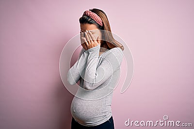 Young beautiful teenager girl pregnant expecting baby over isolated pink background rubbing eyes for fatigue and headache, sleepy Stock Photo