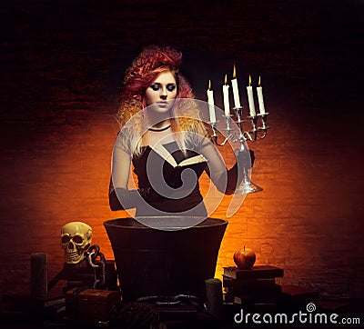 Young and beautiful witch making witchcraft in the dungeon Stock Photo