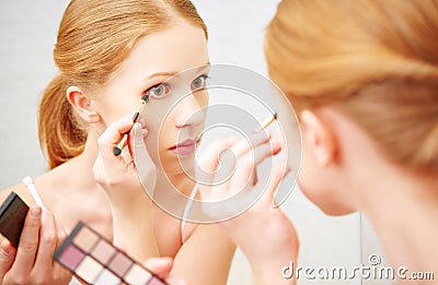 Young beautiful woman apply makeup eyeshadow front of mirror Stock Photo
