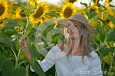 Young beautiful woman on blooming sunflower field in summer Stock Photo