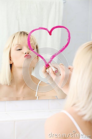 Young beautiful woman drawing big heart on mirror. Stock Photo