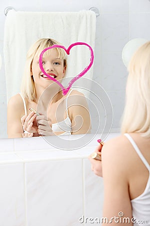 Young beautiful woman drawing big heart on mirror. Stock Photo