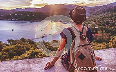 Young beautiful woman hipster traveler looking at sunset and beautiful seascape with a lookout point. Freedom, travel, vacation Stock Photo