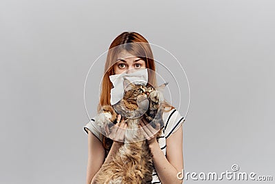 Young beautiful woman holding a cat on a gray background, allergic to pets, runny nose Stock Photo