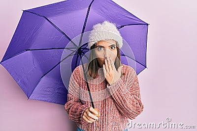 Young beautiful woman holding purple umbrella covering mouth with hand, shocked and afraid for mistake Stock Photo