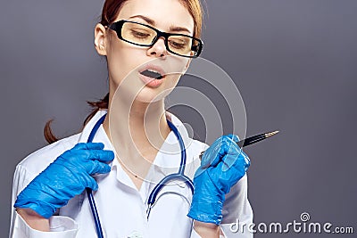Young beautiful woman holding a syringe in a medical dressing gown on a dark gray background Stock Photo