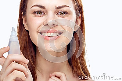 Young beautiful woman holds drops for eyes on white isolated background, portrait, smile Stock Photo