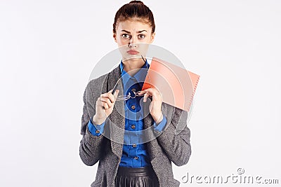 Young beautiful woman holds notebook and glasses, teacher on white background Stock Photo