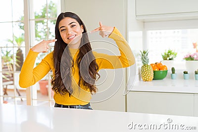 Young beautiful woman at home on white table smiling confident showing and pointing with fingers teeth and mouth Stock Photo