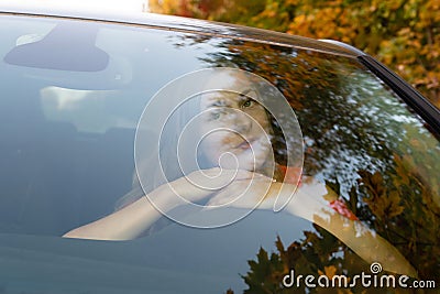 A young, beautiful woman with long hair sits at the wheel. Stock Photo