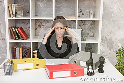 Young beautiful woman manager feeling stressed with folders on her table at her working place in office looking tired. Study Stock Photo