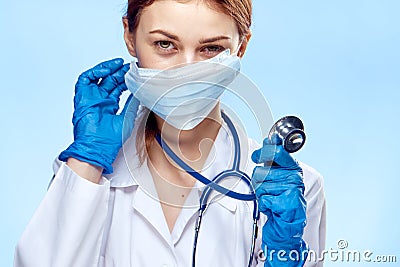 Young beautiful woman in medical clothes holds a stethoscope on a blue background Stock Photo