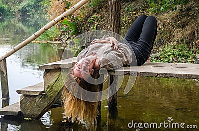 Young beautiful woman model with long blond hair sitting with different emotions laughter, sadness, sorrow, thoughtfulness on a wo Stock Photo